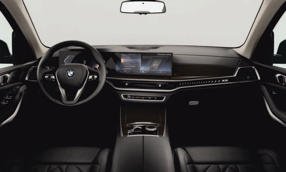 BMW X5 Cockpit mit digitalem Display, eleganten Holzeinlagen und schwarzer Lederausstattung.